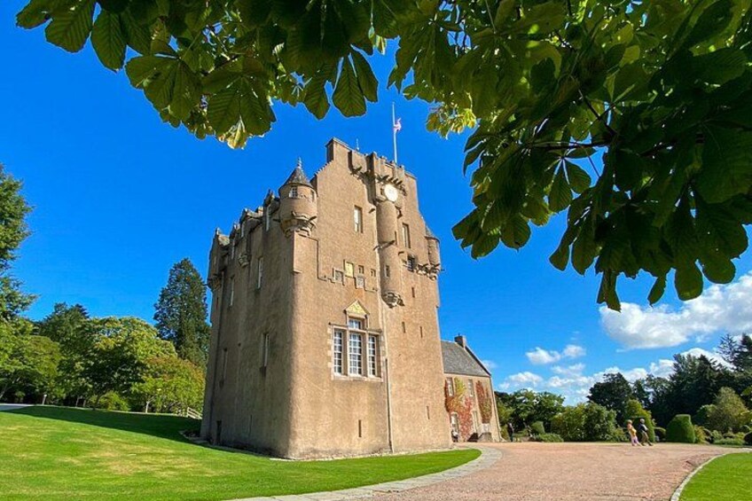 A castle with a tower, surrounded by a well-maintained lawn and trees. 5