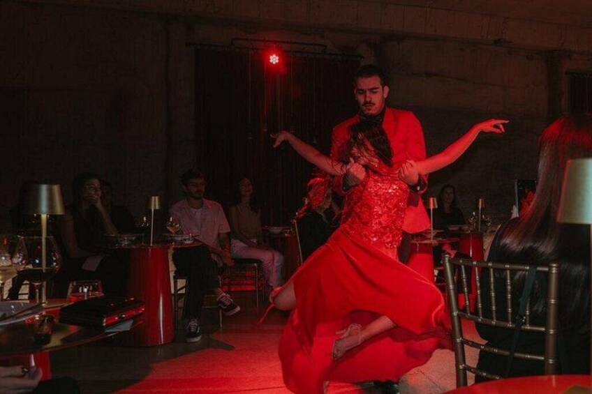 A person in a red dress dancing in a dimly lit room with tables and chairs. 1