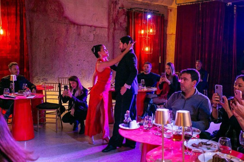 Een stel danst in een restaurant met tafels en stoelen, terwijl mensen aan de tafels zitten. 2