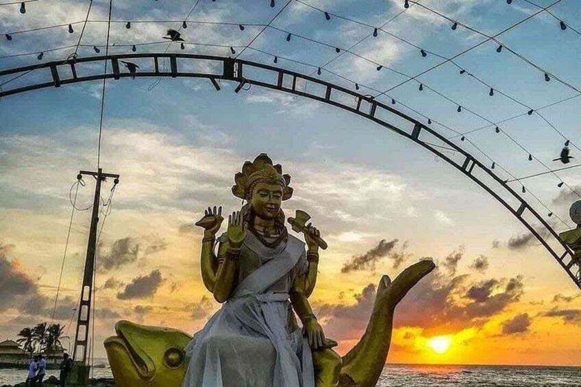 Eine Statue einer Gottheit auf einem Lotusblütenblatt, mit einem Sonnenuntergang im Hintergrund. 2