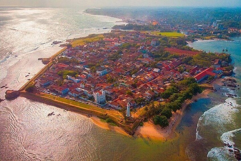 An aerial view of a coastal town with a lighthouse, dense housing, and a beach. 3