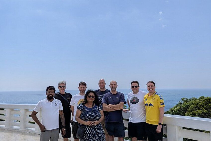 Eine Gruppe von Personen steht auf einem Balkon mit Blick auf den Ozean. 4