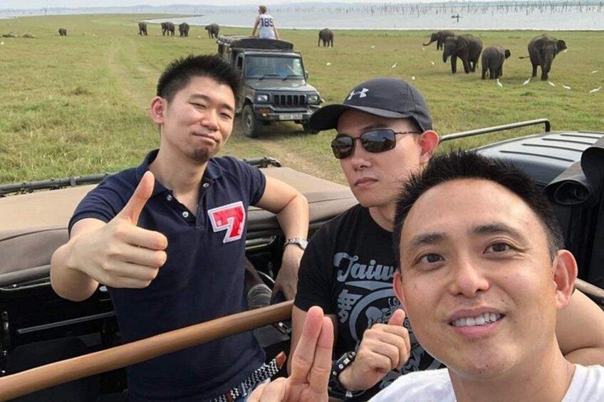 Trois personnes font le signe « pouce levé », un véhicule et des animaux sauvages se trouvent dans un champ herbeux. 1