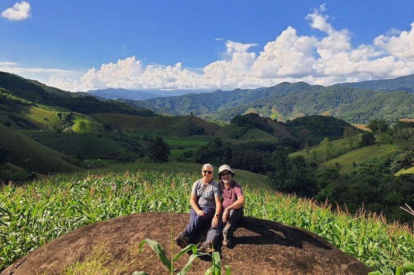 Dos personas sentadas sobre una roca con un paisaje montañoso al fondo. 4