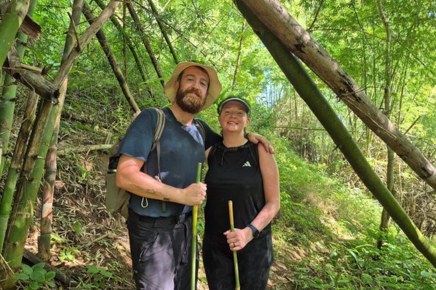 Dos personas caminando por un área boscosa con bambú y abundante vegetación. 2