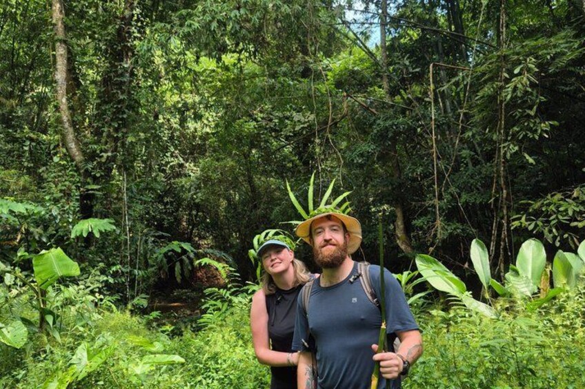 Dos personas caminando por un bosque denso, lleno de vegetación exuberante y diversas plantas. 3