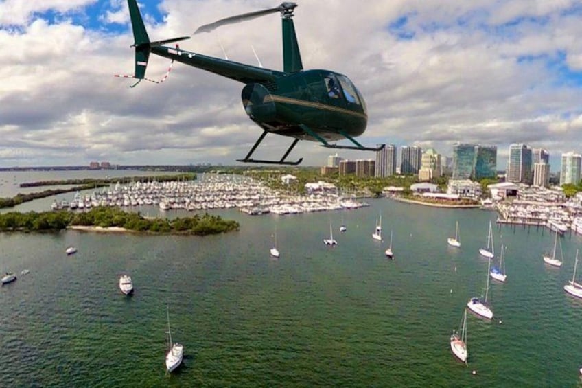 En helikopter flyver over en lysthavn med mange sejlbåde. 3