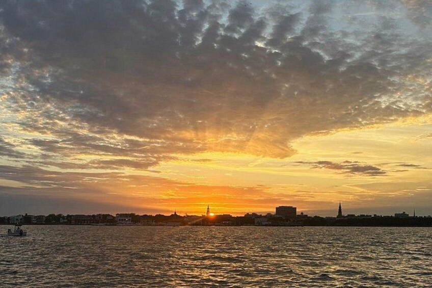 A sunset over a body of water with a city skyline in the background. 2