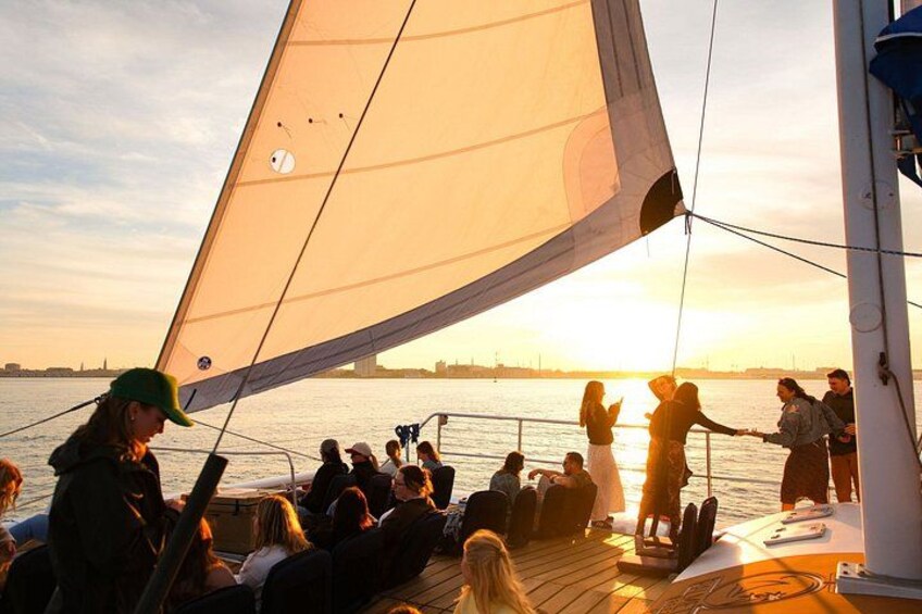 A sailboat with people on deck during sunset. 4