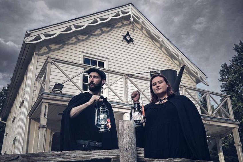 Two people standing in front of a house with a balcony. 2