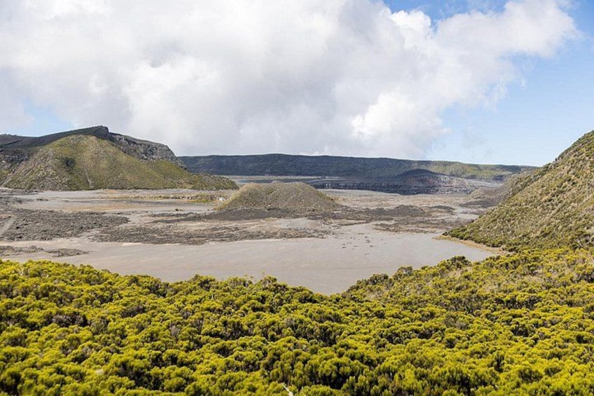 A coastal landscape with green vegetation, rocky hills, and a body of water. 2