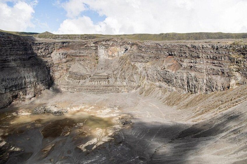 A large open-pit mine with layered rock formations and a visible water body at the bottom. 5