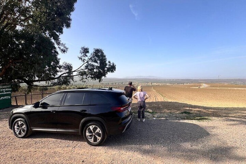 A black SUV parked on a gravel path with a clear view of a vast, open landscape and distant mountains. 5