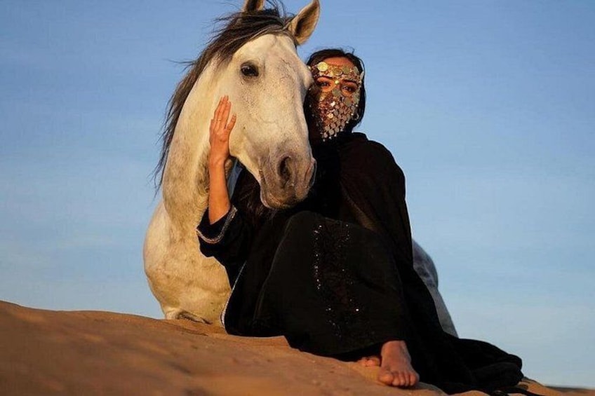 Une personne assise sur une dune de sable, avec un cheval blanc. 4