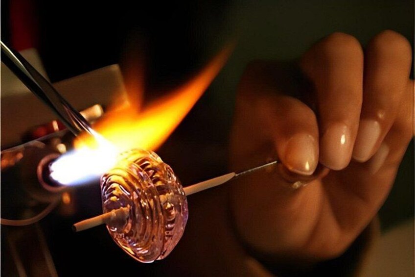 A person using a blowtorch to heat a glass object. 1