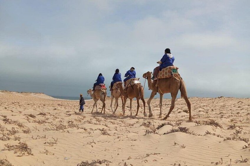 A group of people riding camels across a sandy desert landscape. 3