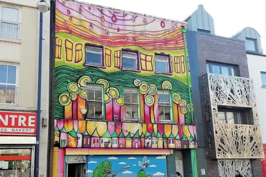 A colorful building with a mural, a bakery sign, and a decorative lattice structure. 3