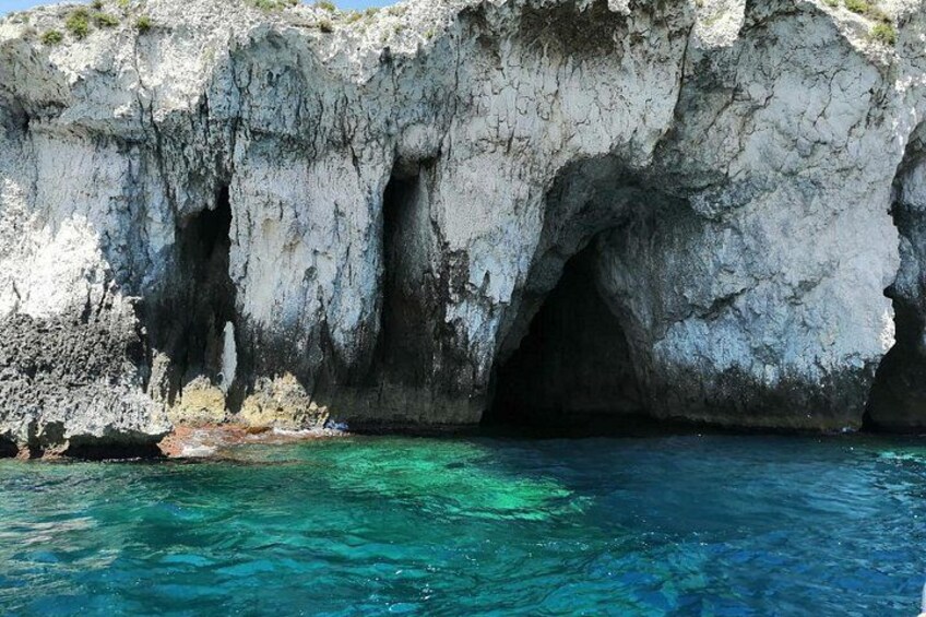 Une falaise côtière avec une entrée de grotte et une eau d’un bleu limpide. 4