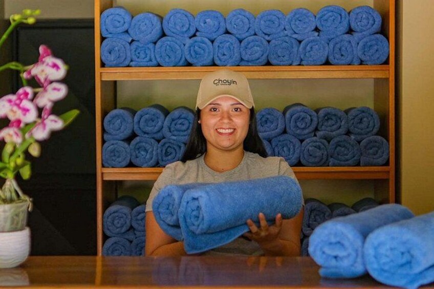 Una persona sostiene toallas azules enrolladas frente a un estante con más toallas azules enrolladas. 4