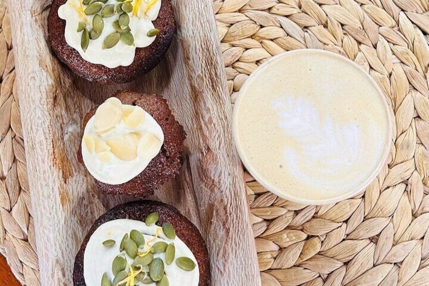 Three muffins topped with cream and seeds, and a latte art cup. 2