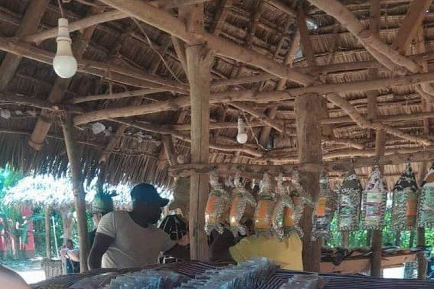 A rustic wooden structure with a thatched roof, hanging decorations, and a light bulb. 5