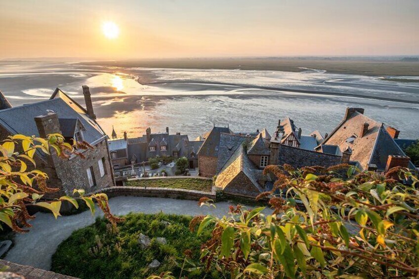 A coastal town with stone buildings and a view of the sea at sunset. 4