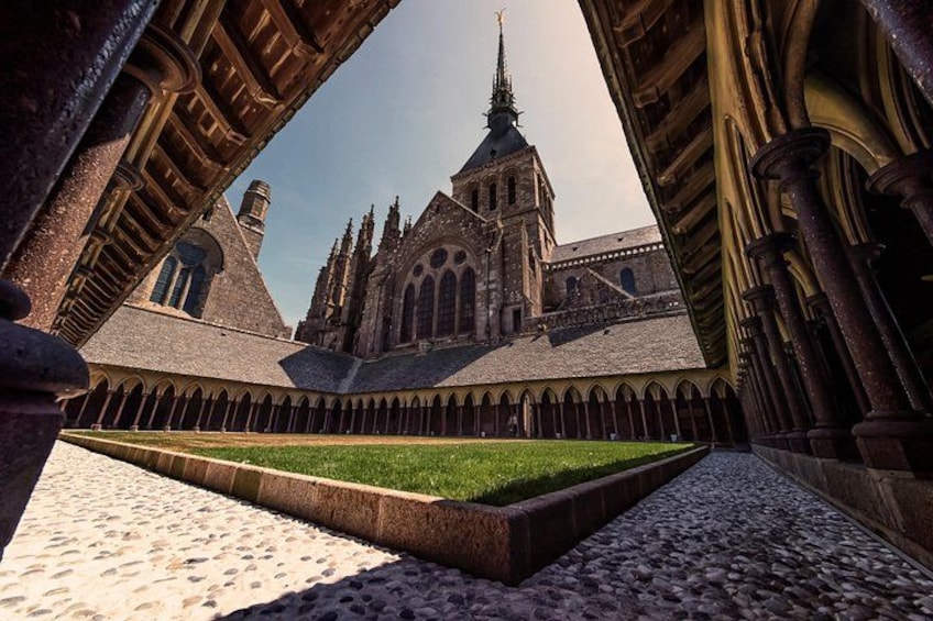 A cathedral with a tall spire, a cloister with a central lawn, and stone arches. 4
