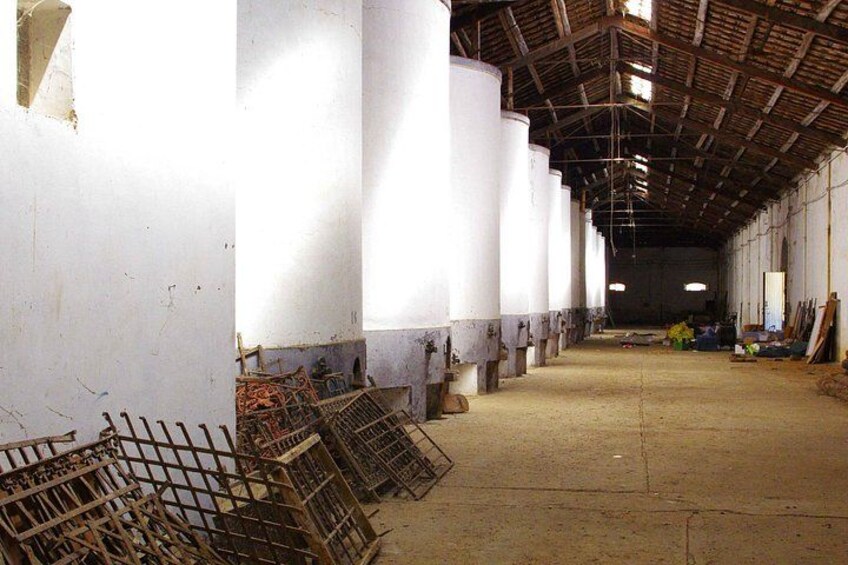 A warehouse with large white storage tanks, metal racks, and a concrete floor. 4