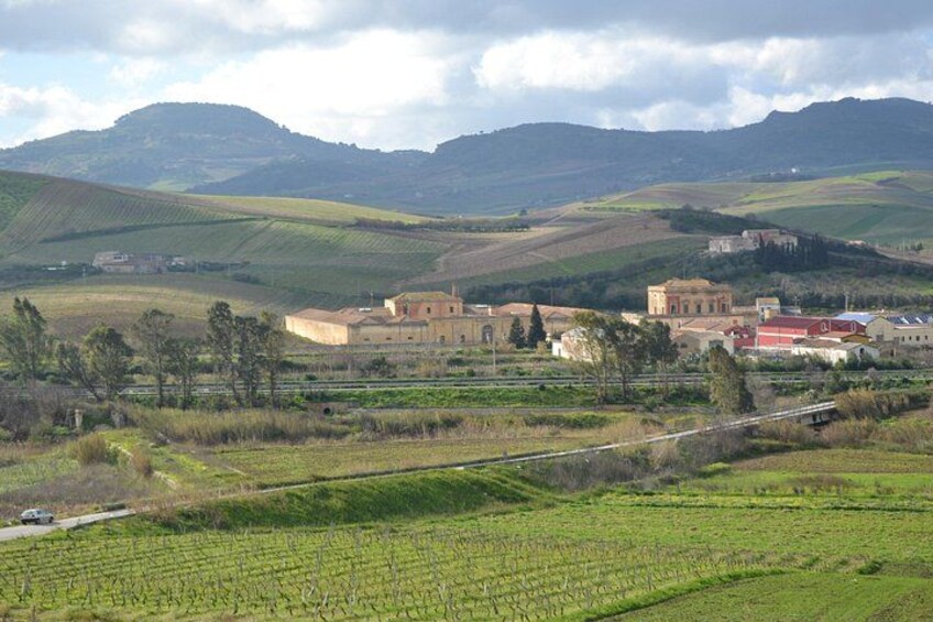 A vineyard, a historic building, and rolling hills in the background. 1