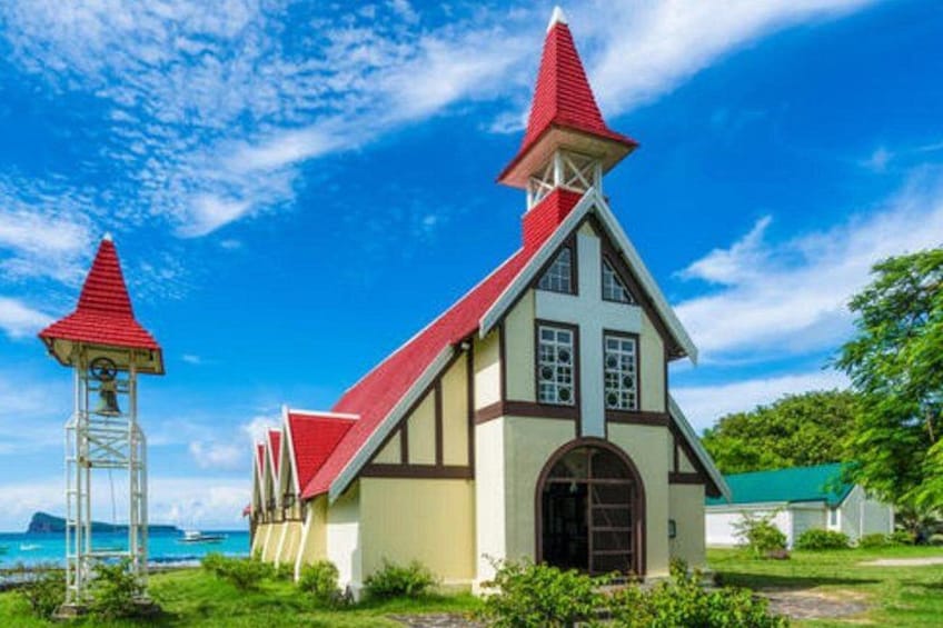 Een kerk met een rood dak en witte muren, een klokkentoren en uitzicht op de oceaan. 5