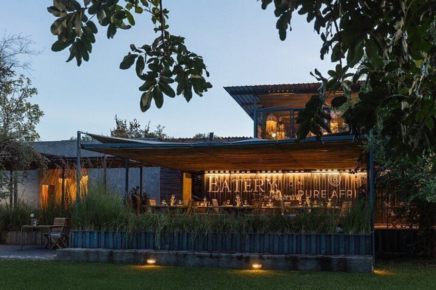 A modern building with a covered outdoor area, surrounded by greenery. 2