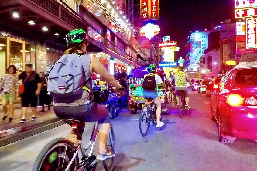 A busy street at night with neon signs and bicycles. 1