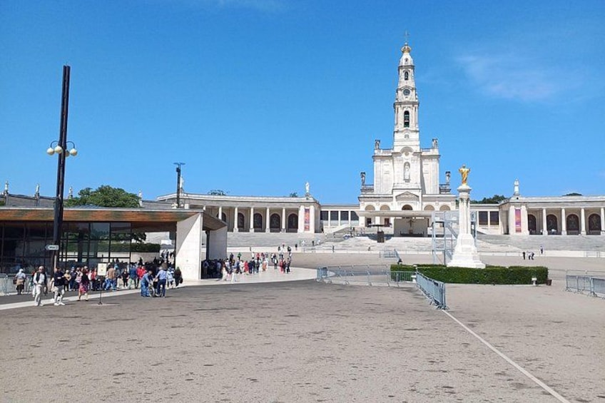 Una plaza con un edificio blanco grande que tiene un campanario, rodeada por una multitud de personas. 1