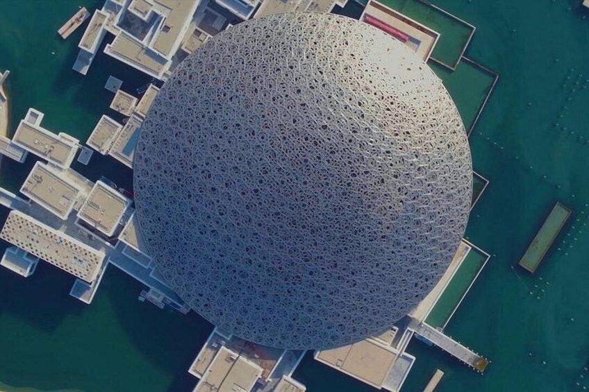 Una gran estructura esférica con superficie perforada, rodeada de edificios y agua. 4