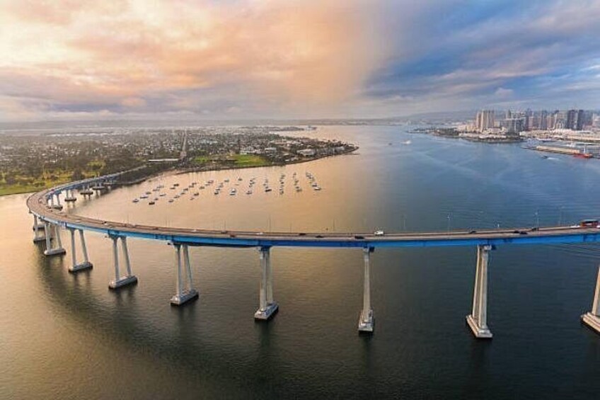 Un puente sobre una masa de agua con barcos, una silueta urbana y un cielo nublado. 3
