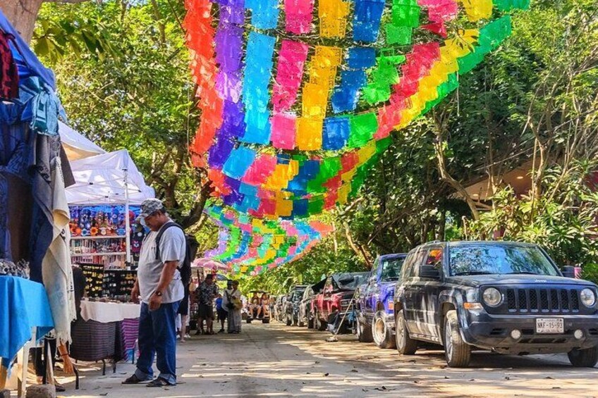A street market with colorful decorations and parked vehicles. 2