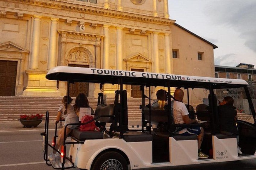 Un autobus touristique rempli de passagers est garé devant un grand bâtiment orné de colonnes et doté d’une horloge. 5