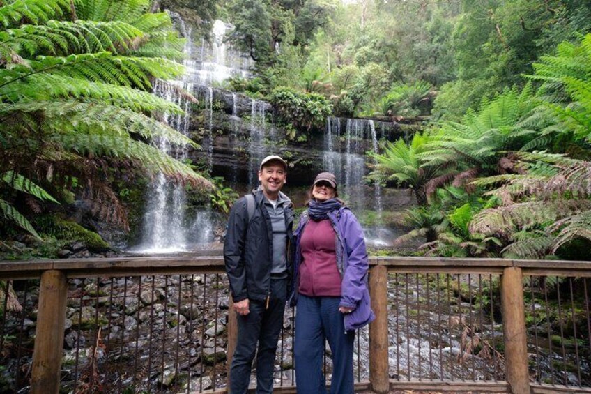 Una pareja parada junto a una cascada en un bosque verde y exuberante. 4