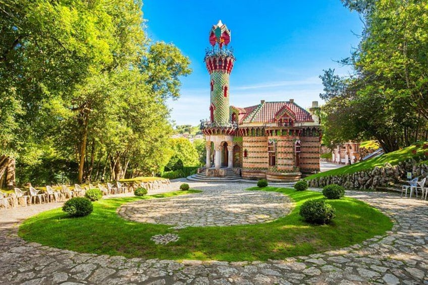Een kasteel met een hoge toren, omgeven door bomen en een stenen pad. 1