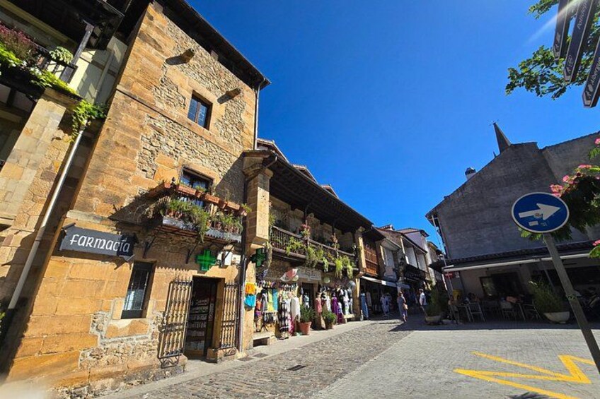 A cobblestone street with buildings, a pharmacy sign, and a blue directional sign. 2