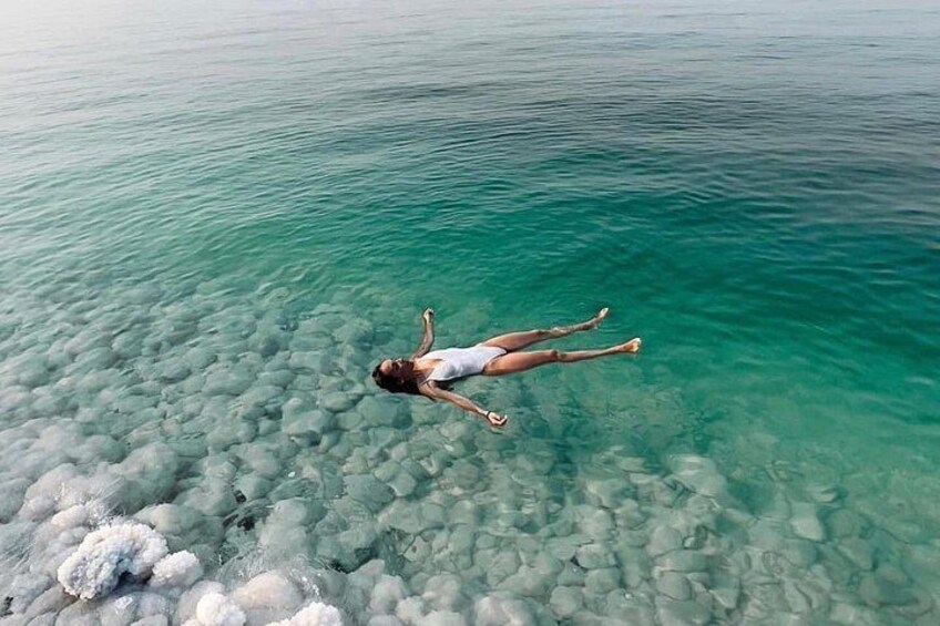Una persona che galleggia sull'acqua, con rocce chiare visibili sotto. 2