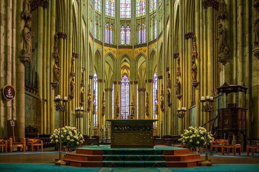 A cathedral interior with high vaulted ceilings, stained glass windows, and a central altar. 5