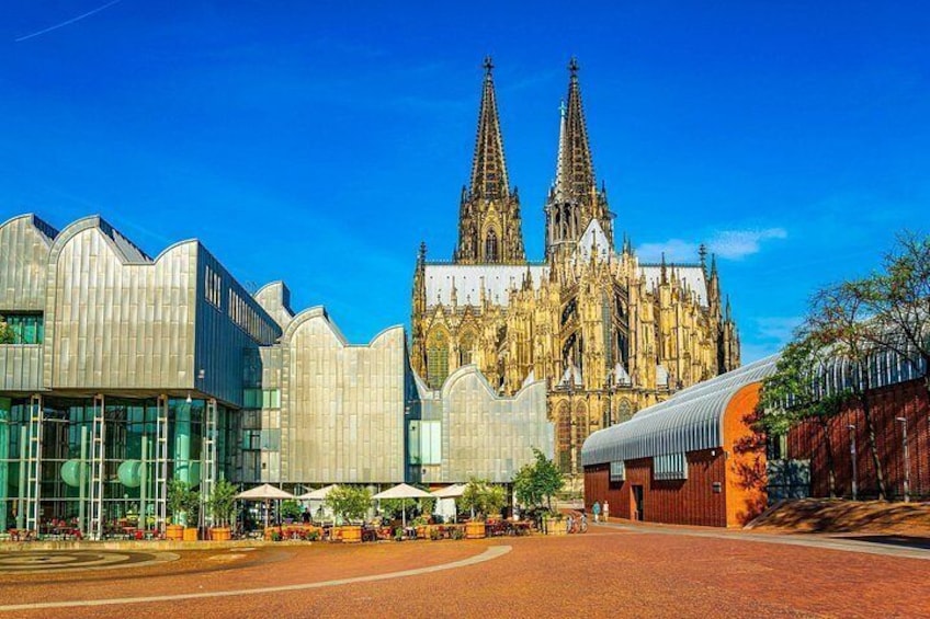 A cathedral with two spires, modern buildings, and a red brick plaza. 3
