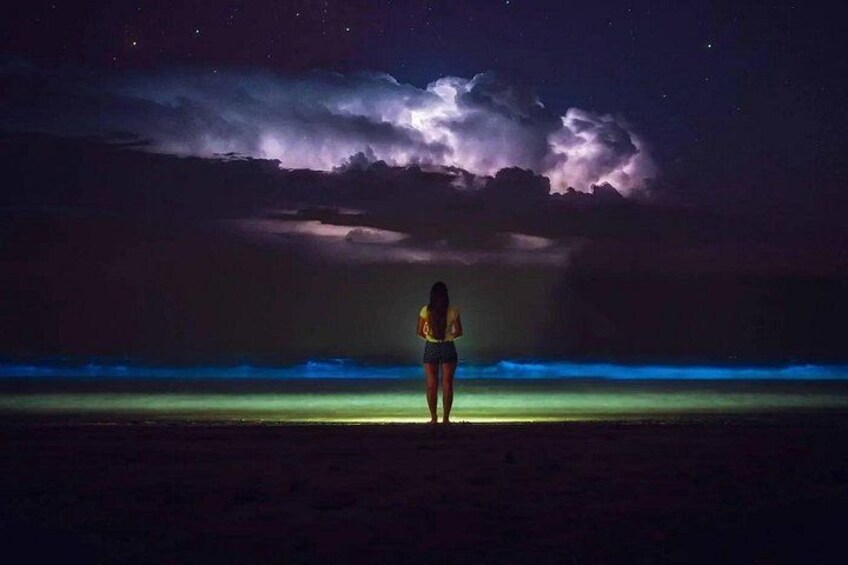 Una persona in piedi su una spiaggia di notte, sotto un cielo suggestivo. 3