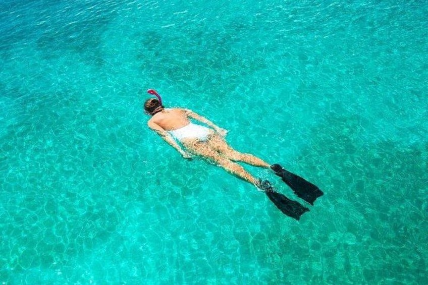 A person snorkeling in clear turquoise water. 4
