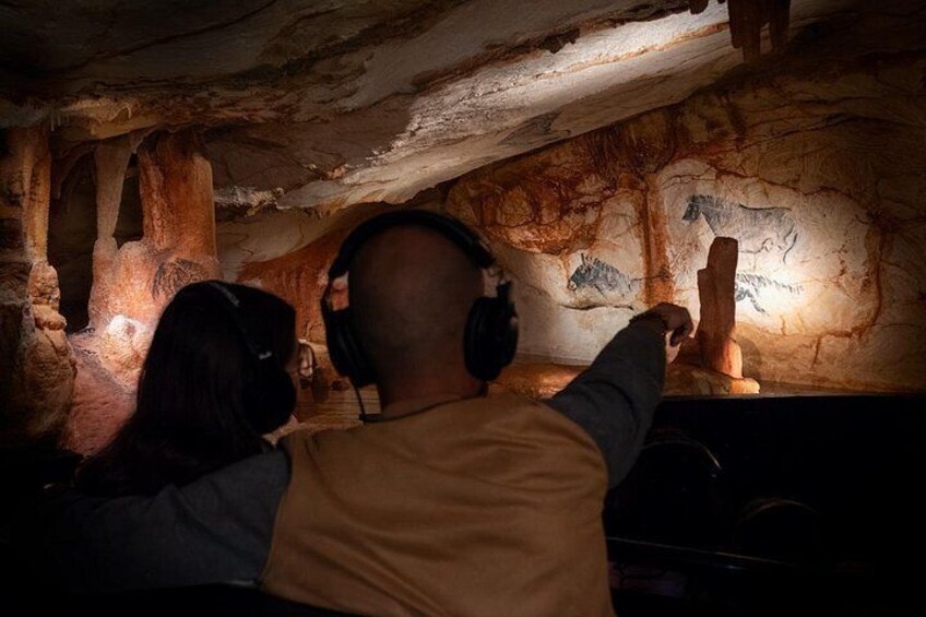 A person pointing at cave wall paintings. 2