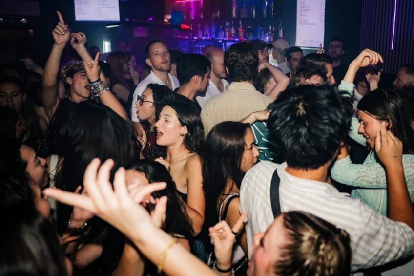 Un espace intérieur bondé où les gens dansent et socialisent. 4