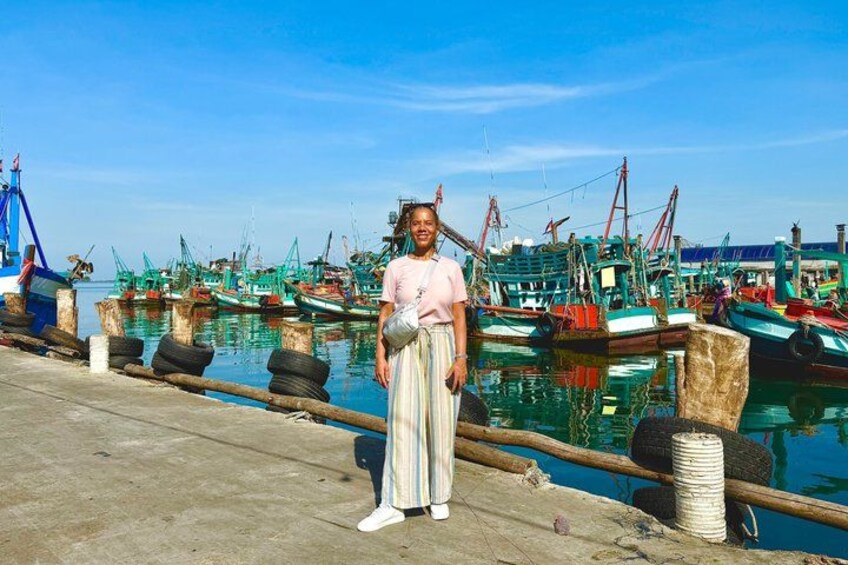 Una persona está de pie en un muelle, con barcos de pesca al fondo. 2