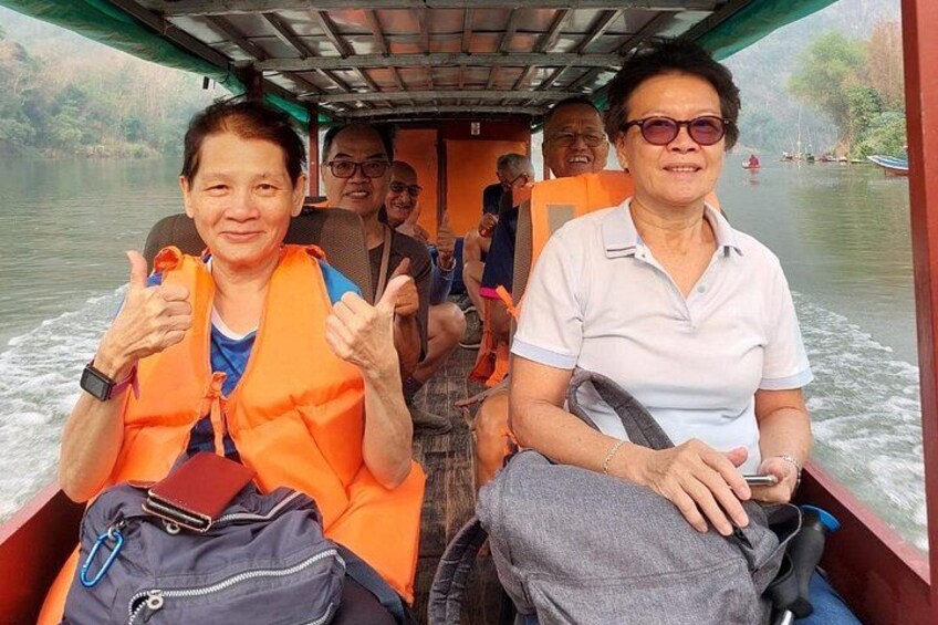 People on a boat with life jackets, water, and greenery in the background. 2