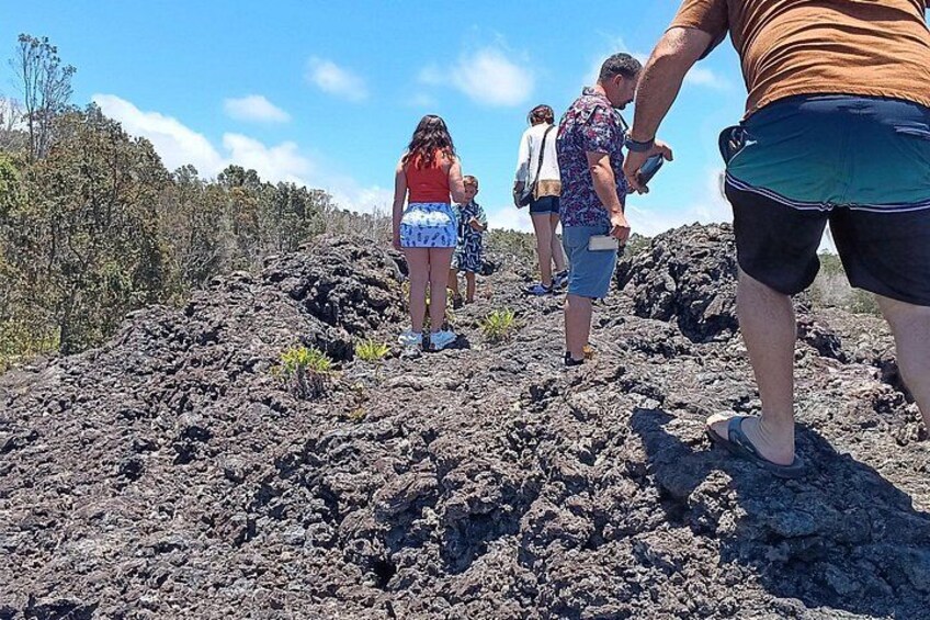 Un groupe de personnes fait de la randonnée sur un terrain volcanique où la végétation est rare. 1